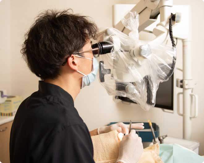 さいとう歯科クリニック院長の齋藤彰が顕微鏡を覗き込んで検査をしている写真